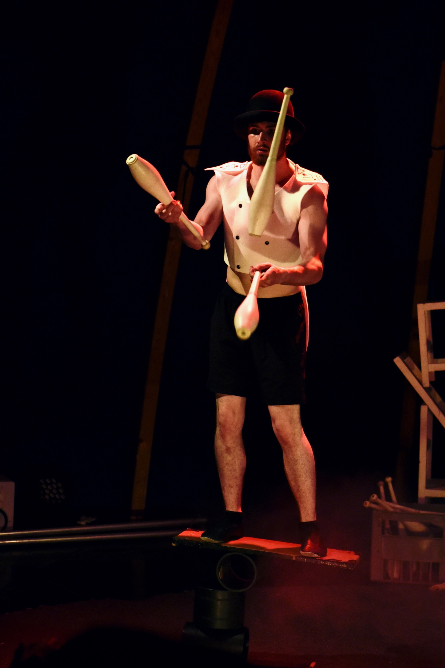 Jongleur de Cirque-en-Ciel en équilibre sur une planche, manipulant des massues